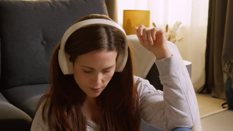 Mujer-Con-Auriculares-Inalámbricos-Sentada-En-El-Suelo-En-Casa-Transmitiendo-Música-Desde-Un-Teléfono-Móvil-6